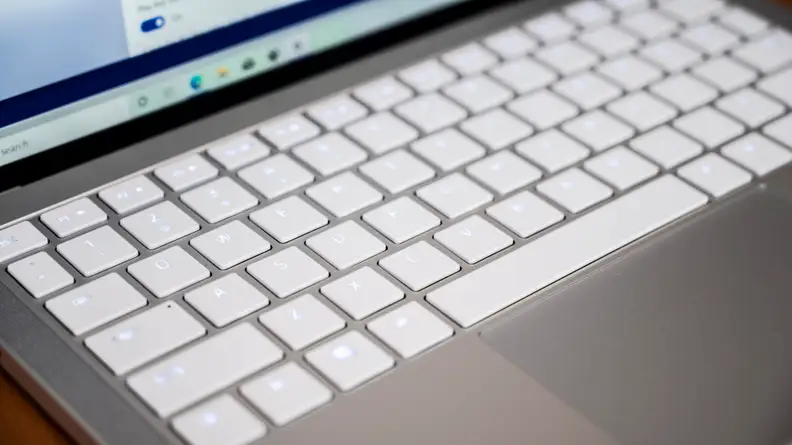 The laptop's keyboard is shown, white keys on a silver chassis.