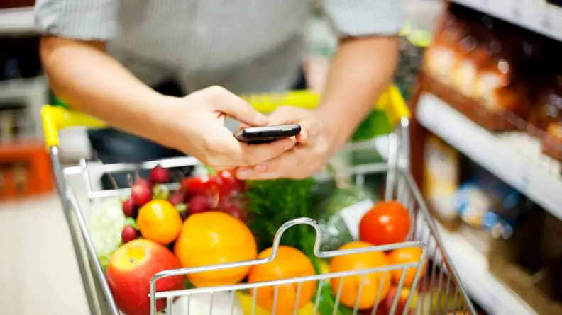 A person on their phone while grocery shopping.