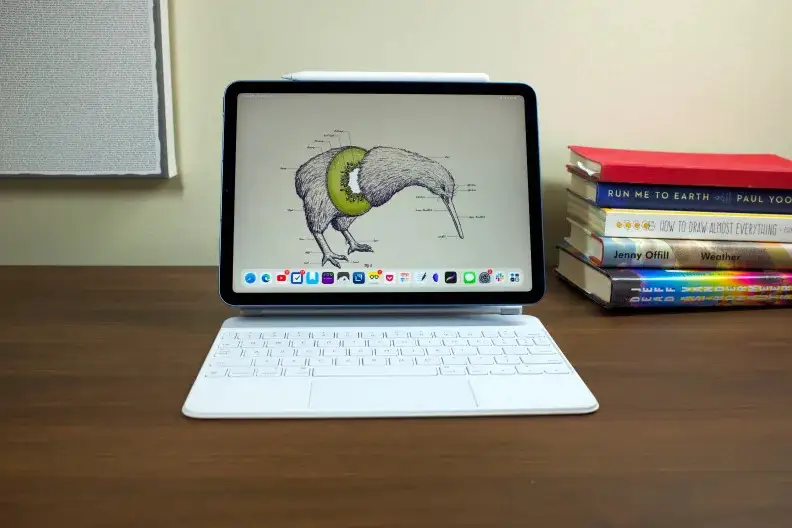 Apple's iPad Air, docked into the Magic Keyboard (white), with a wallpaper of a kiwi bird showing on the display.