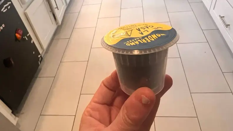 Person holding a Bruvi coffee pod in their fingers.