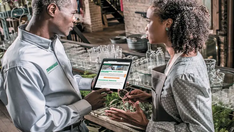 Technician showing a tablet with pest control services to a client
