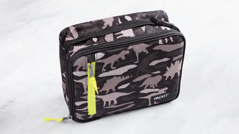 The PackIt Freezable Classic Lunch Box in dinosaur camo pattern on a marble counter.