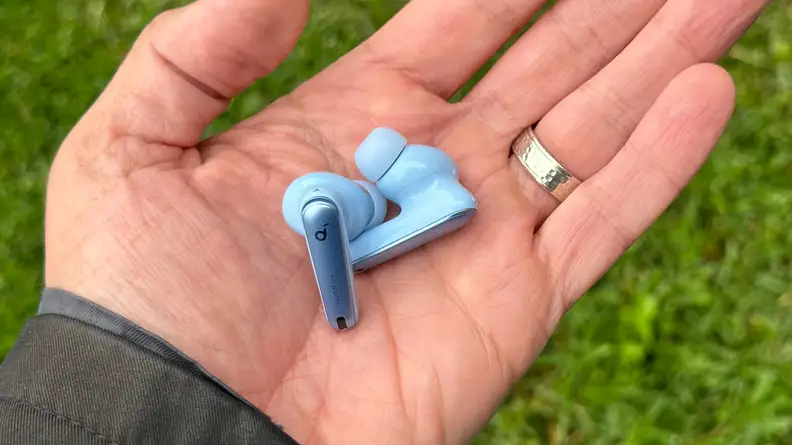 A hand holding the blue Anker Soundcore Liberty 4 NC earbuds.