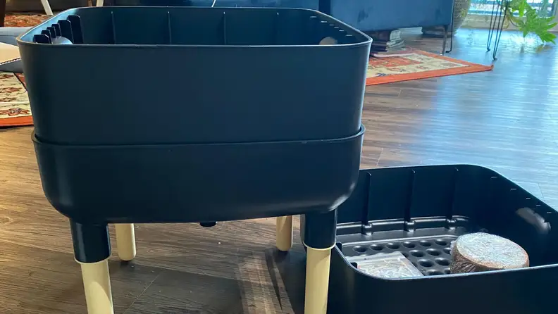 Small black compost bin on floor next to composting supplies.