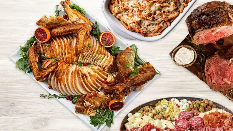 Holiday spread with sliced turkey, baked pasta, prime rib, and antipasto
