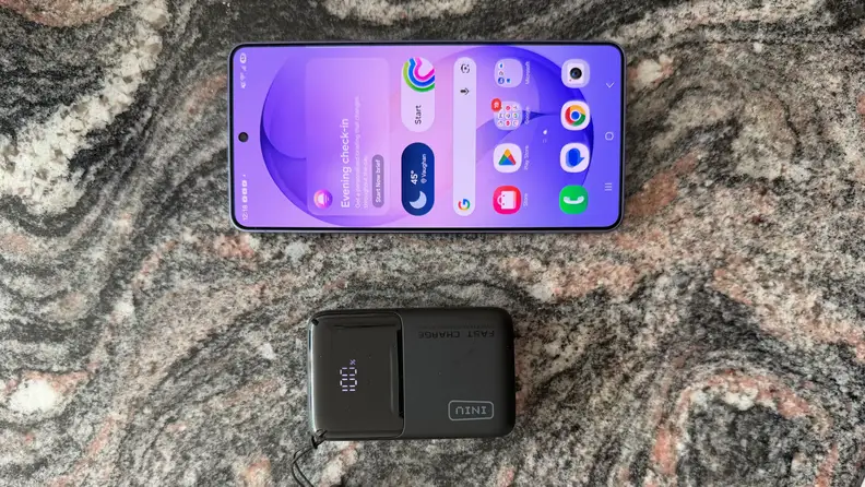 iPhone and INIU Pocket Rocket 50 portable charger sitting on a dark grey marble counter.