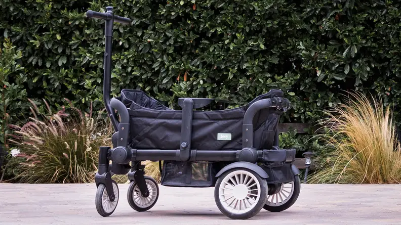 A Joey stroller wagon outside in front of a hedge.