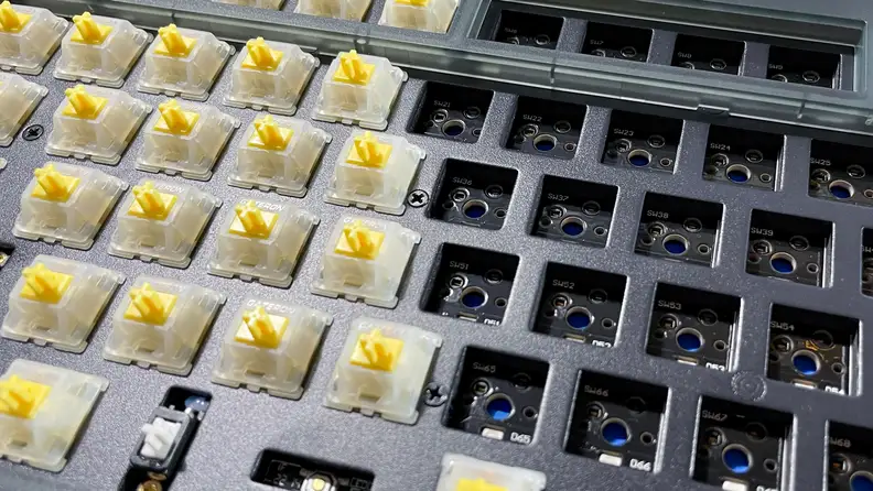 A board of a keyboard half with switches without keycaps and the other half with empty sockets.