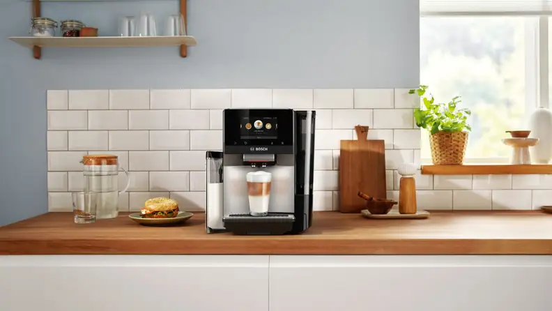 Bosch espresso machine with a prepared latte at the base, shot in a kitchen setting