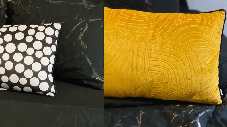 Reversible throw pillow with black and white polka dots on one side and a gold leaf pattern on the other.
