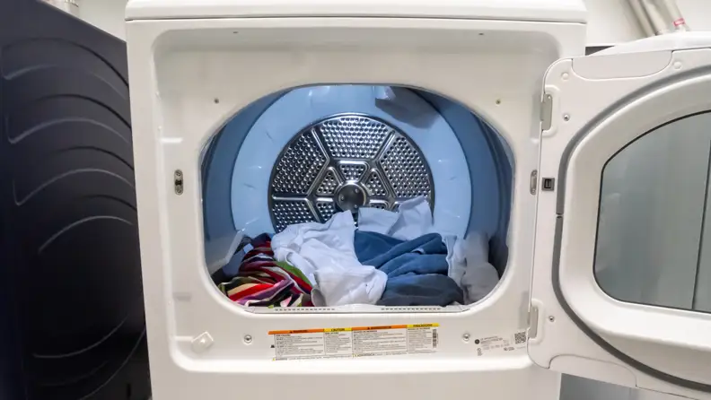 We can see into the stainless steel drum of the GE GTD72EBSNWS, illuminated by its internal LED. There are colorful towels and clothes in the drum.
