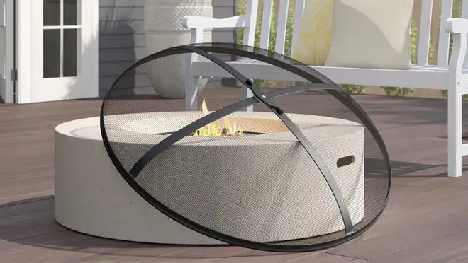 Stone fire pit with cover on patio next to white bench.