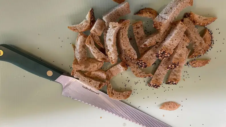 Pile of sliced pieces of bread next to knife.