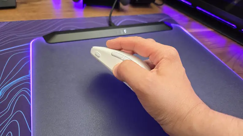 A hand gripping the Turtle Beach Burst II Air mouse on top of a purple and blue patterned mousepad.