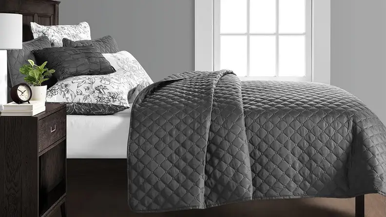 Gray and white comforter set on bed in bedroom.