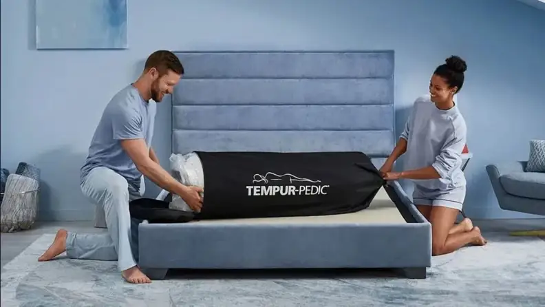 a couple set up a Tempur-Pedic on a bed frame