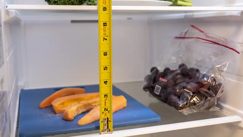 A close-up of the Samsung RS27T5561SR side-by-side refrigerator's shelves, with measuring tape to show each shelf has about 9 inches of clearance.