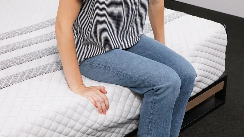 A person sitting on the edge of the Leesa Sapira hybrid mattress