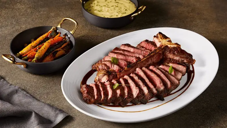 Chopped bone in porterhouse with mashed potato and cooked veggies on the side