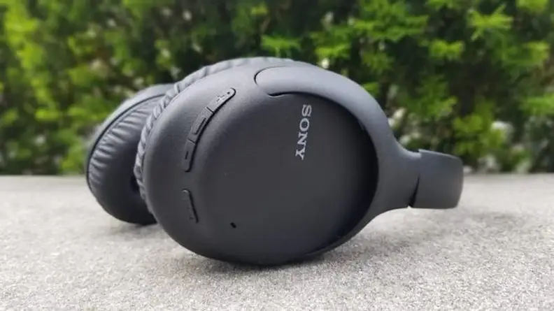 A pair of Sony headphones have been laid on their side. Volume controls are visible along the curvature of one earpiece.