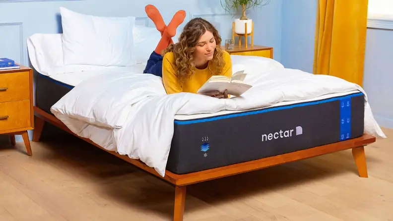 a person lies on the Nectar mattress reading a book