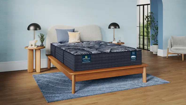 The Serta Perfect Sleeper X hybrid mattress on a wooden bed frame in a blue bedroom.