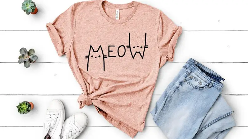 a pink t-shirt that says meow on a white background