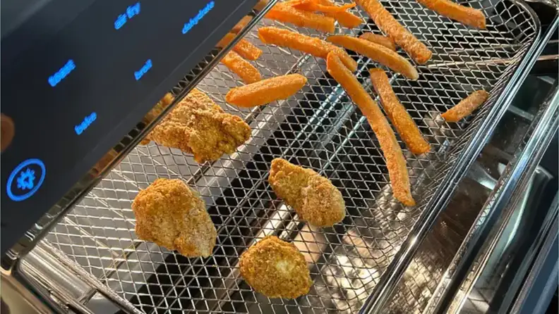 Chicken nuggets and french fries shown in the Our Place Wonder Oven Pro air fryer.