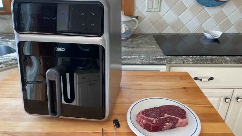 The Dreo ChefMaker Combi Fryer on top of wooden countertop surface next to raw steak on top small plate.