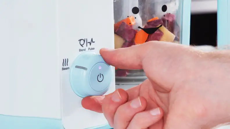 A person turning a dial on the Nutribullet Baby Steam + Blend.