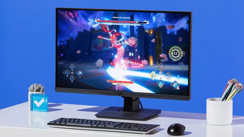 Asus ROG Strix XG27ACS monitor on a desk against a blue wall