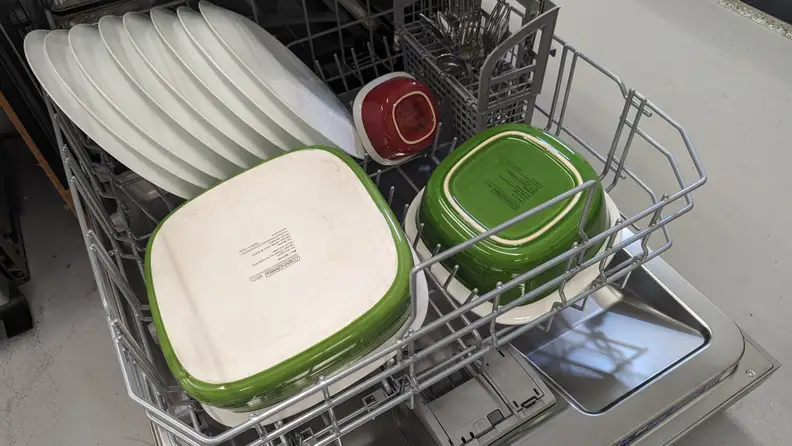 A close-up of the bottom rack of the Bosch dishwasher, filled with plates, ceramic cookware, and utensils.