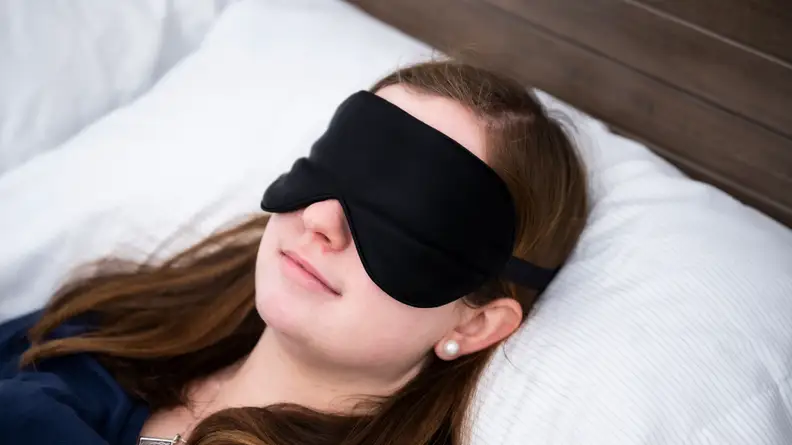 Sara Tabin sleeping in a black Alaska Bear mask.