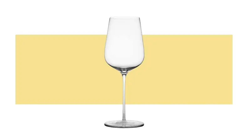 A single white wine glass on a yellow background.