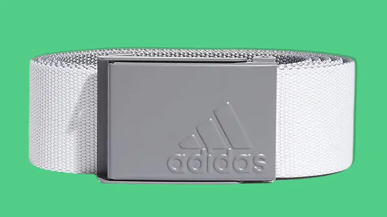 Adidas Golf Reversible Web Belt on green background.