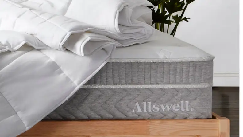 Allswell mattress with a duvet on top and brown wood bedframe