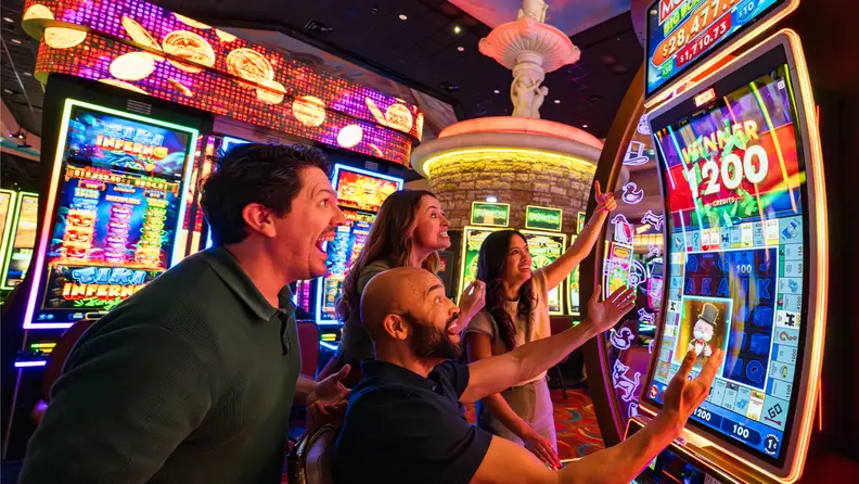 Guests celebrating a win at a slot machine inside WinStar World Casino and Resort, surrounded by bright casino lights and gaming machines.