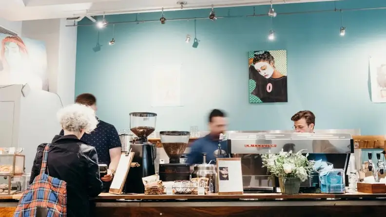 Baristas working behind the counter in a cafe with art on walls