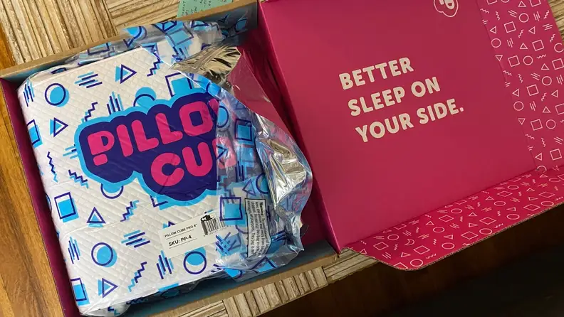 the pillow cube in its box on a brown wood table