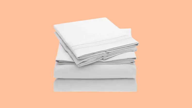 A light colored stack of twin XL bed sheets float above an empty peach background.