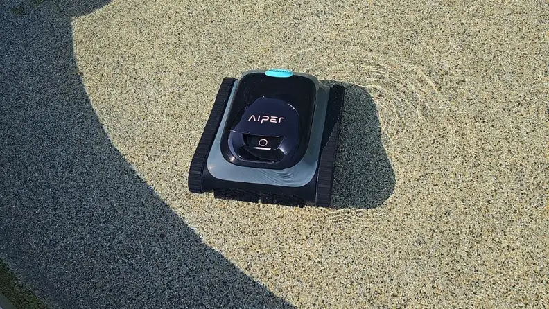 The Aiper Scuba S1 robotic pool cleaner sits in the shallow end of a pool.