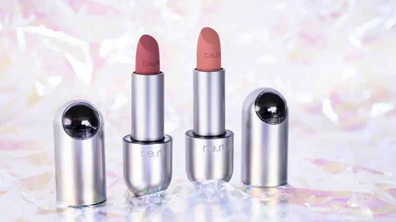 Two lipsticks standing with their caps to the side of them.