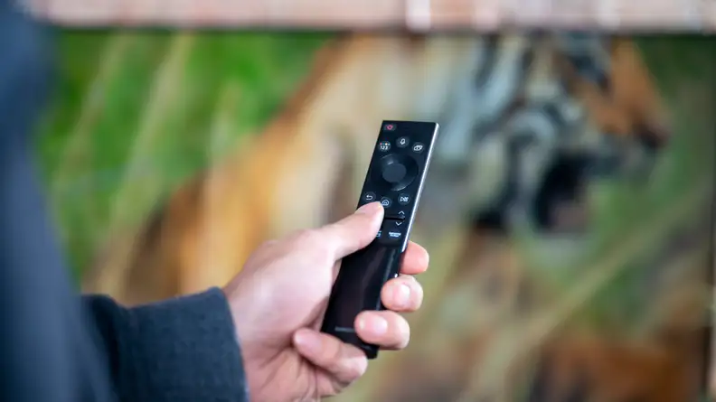 A close-up of the Samsung Solar Cell remote control being held in someone's hand