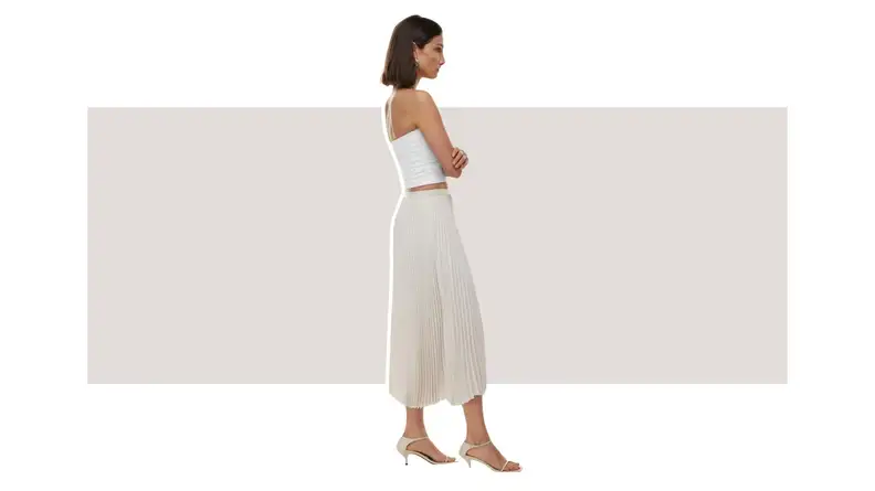 A model wearing a white pleated skirt with an asymmetrical hem.