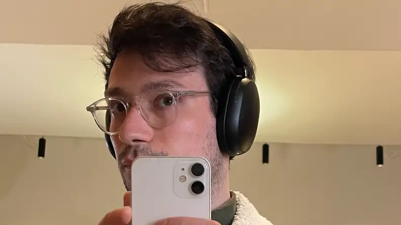 Person taking a mirror photo with smartphone while wearing the Sonos Ace headphones on ears.