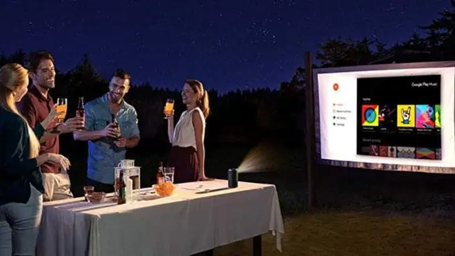 A group of people outside watching a movie on a big screen