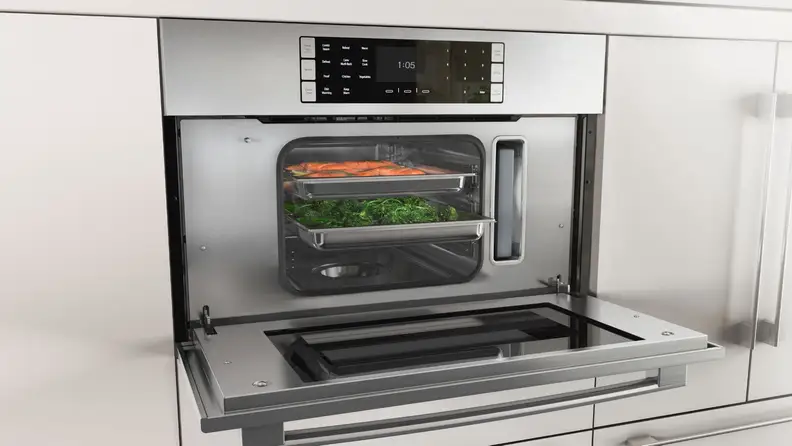 A photo of a steam oven with its door open and food steaming inside.