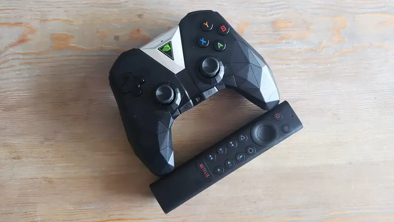 A game controller next to a TV remote