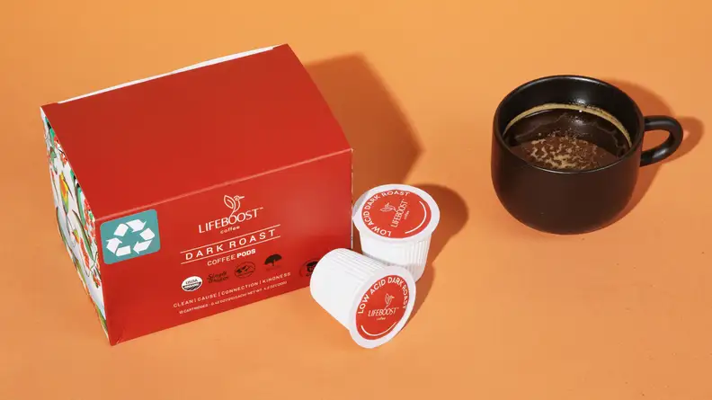 A red box of Lifeboost Coffee's pods and a black cup of coffee next to it, on an orange background.