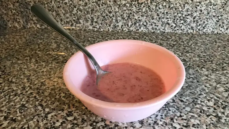 A pink bowl of frozen shaved fruit on a marble countertop.